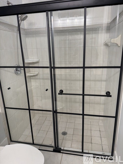 A white toilet is in the corner of a tiled bathroom.