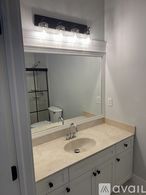 A bathroom with a sink, mirror, and lights above it.