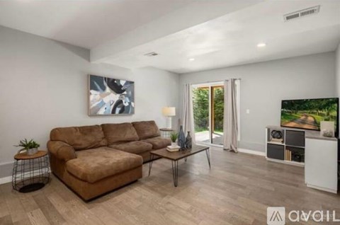 A living room with a brown sofa and a painting on the wall.