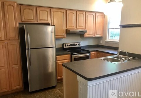 A kitchen with wooden cabinets and a stainless steel refrigerator.