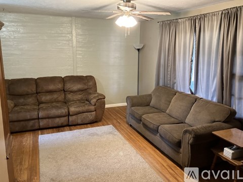 A living room with two brown couches and a white rug.