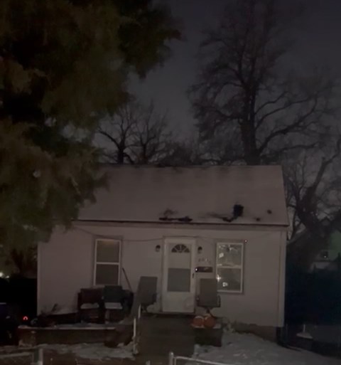 A house with a snow-covered roof and a dark sky.