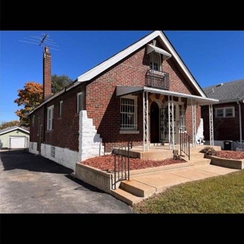 A red brick house with a white porch.
