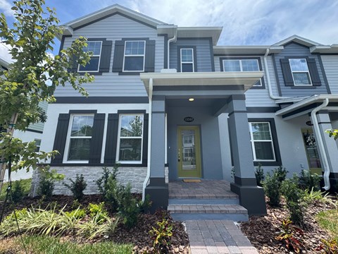 A grey house with a green door and a small porch.