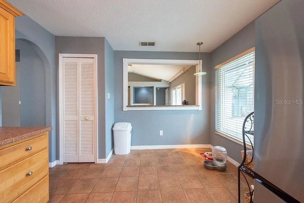 A kitchen with a brown tile floor and a white trash can.