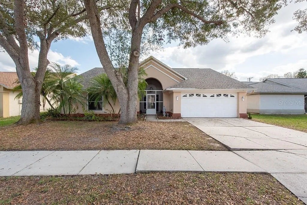 A house with a driveway and trees in front.