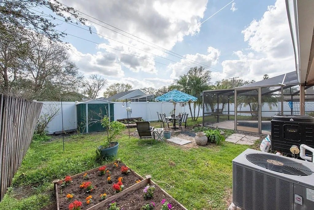A backyard with a vegetable garden, patio furniture, and a pool.