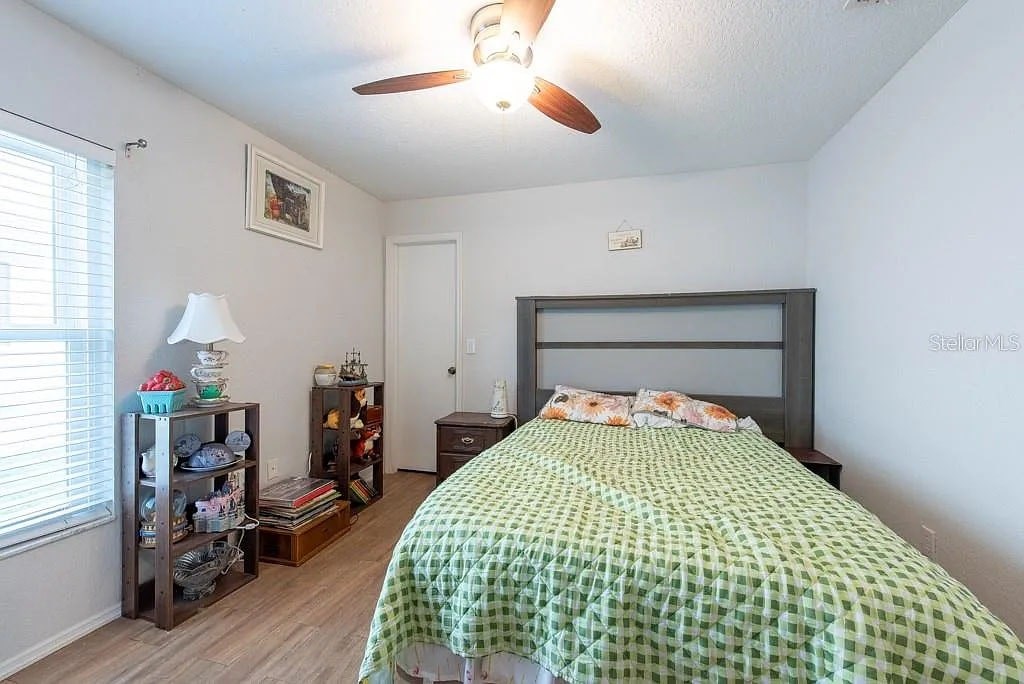 A bedroom with a bed, a ceiling fan, and a window with blinds.