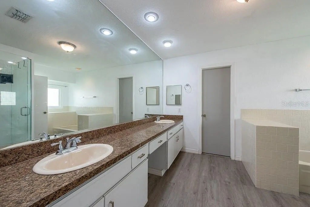 A bathroom with a sink, mirror, and a shower.