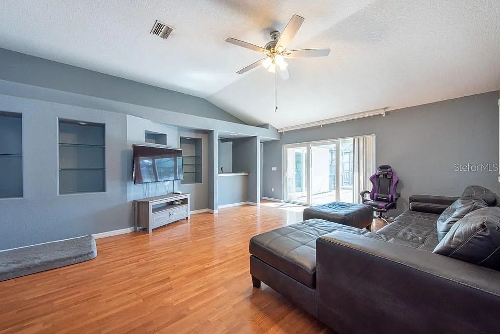 A living room with a grey couch and a ceiling fan.
