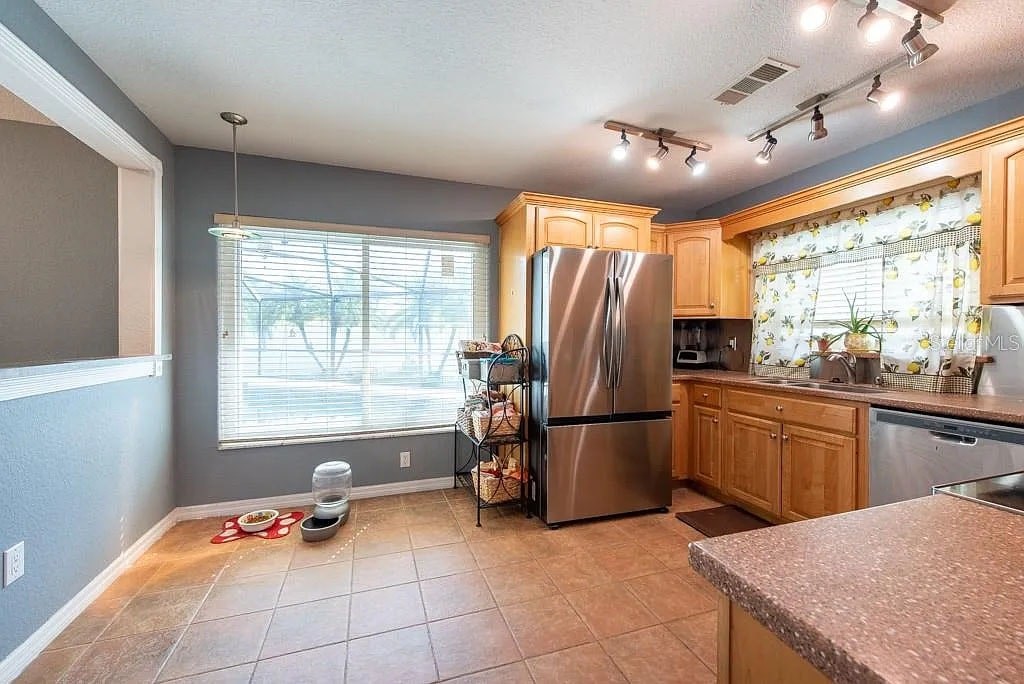 A kitchen with a refrigerator, sink, and window.