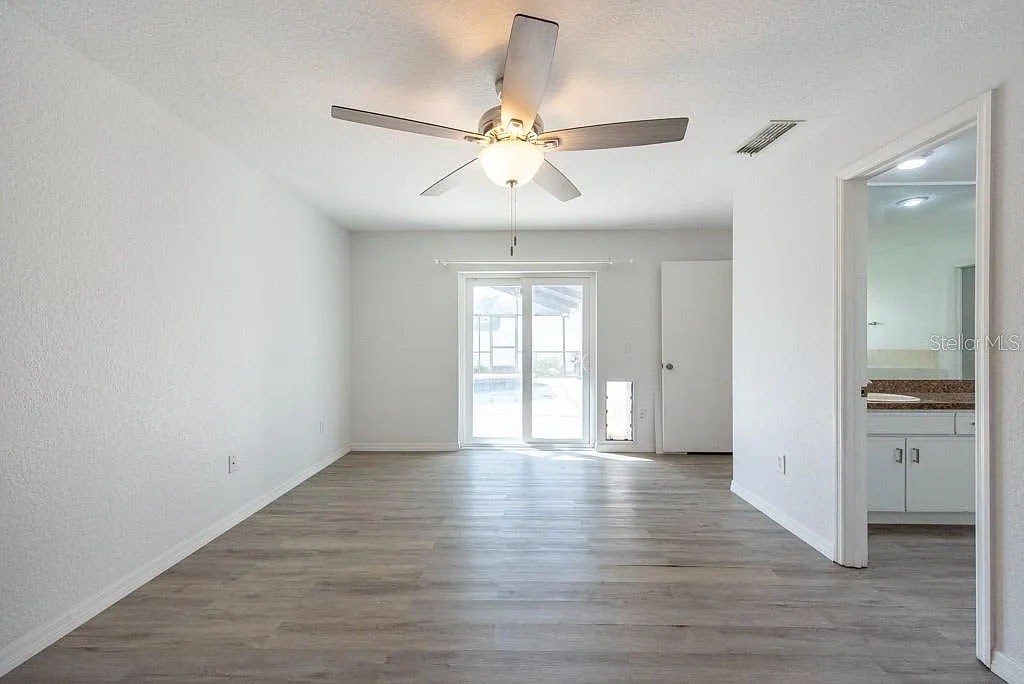 A spacious room with a ceiling fan and wooden flooring.