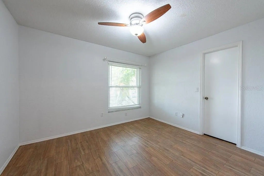 A room with a ceiling fan and wooden flooring.
