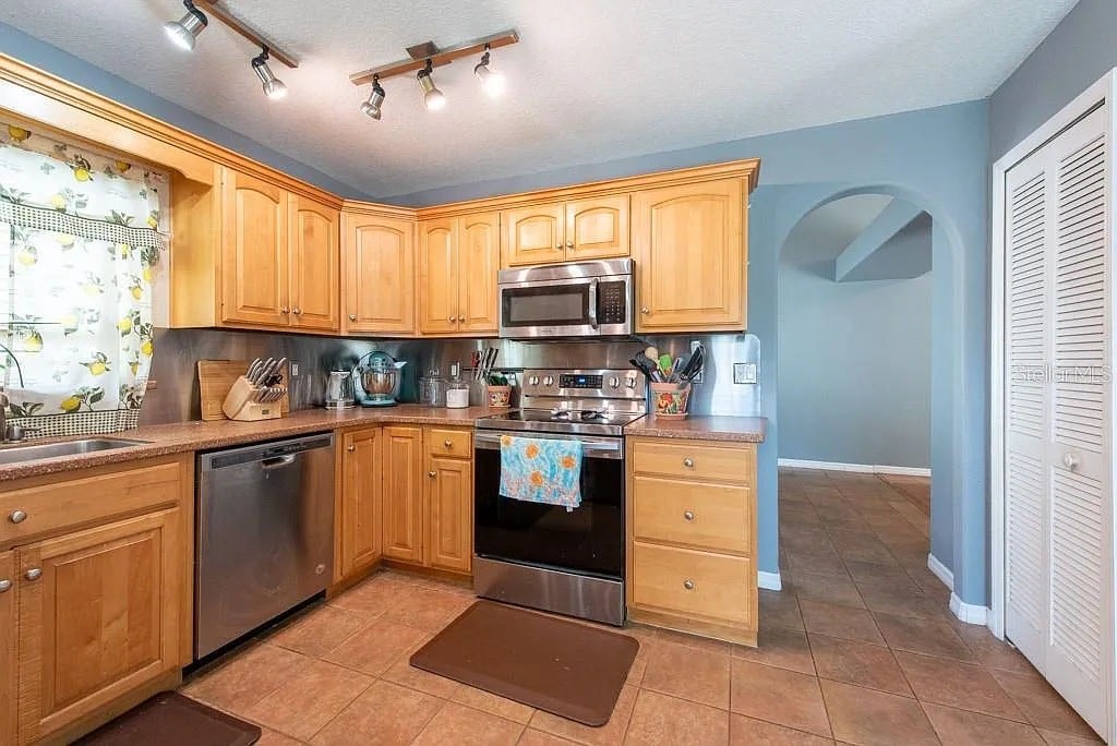 A kitchen with wooden cabinets and a microwave on top of the stove.
