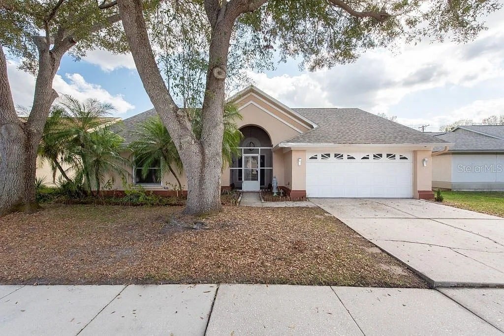 A house with a driveway and a tree in front.