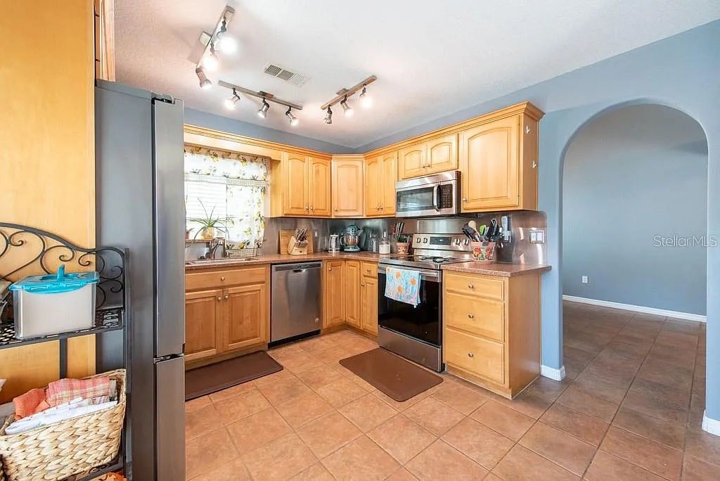 A kitchen with wooden cabinets and a tile floor.