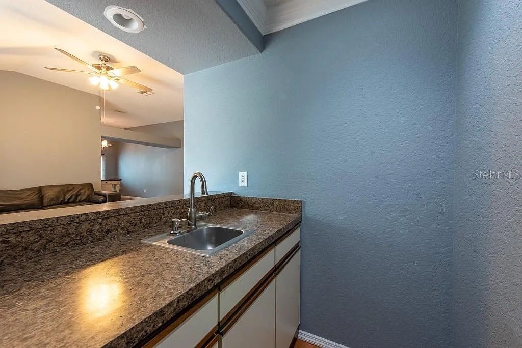 A kitchen with a granite countertop and a stainless steel sink.
