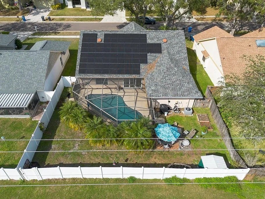 A house with a solar panel on the roof and a pool in the backyard.