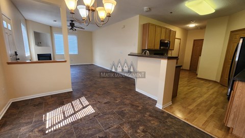 A living room with a brown floor and a ceiling fan.