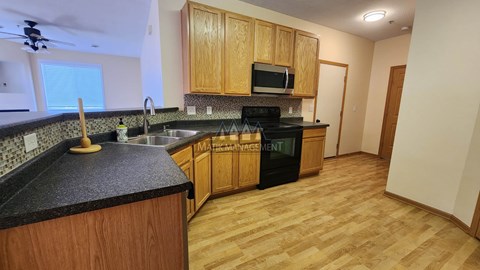 A kitchen with wooden cabinets and a black counter top.