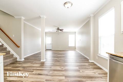 A spacious room with wooden flooring and a staircase leading to the upper level.