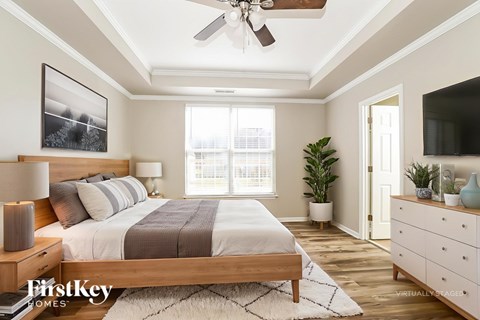 A bedroom with a bed, a ceiling fan, and a window.