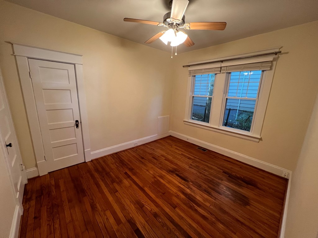 A room with a ceiling fan and a window with blinds.