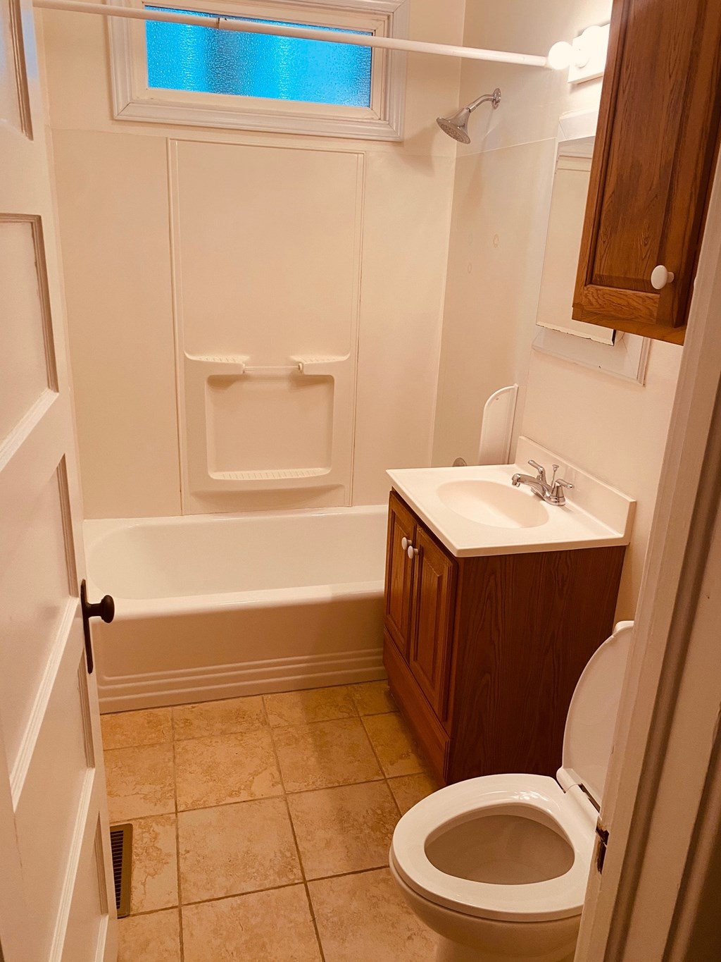 A white toilet in a bathroom with a white tub and sink.