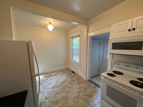 A kitchen with a white stove top oven and a white microwave above it.