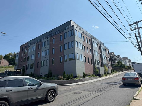 A modern apartment building with a car parked in front.