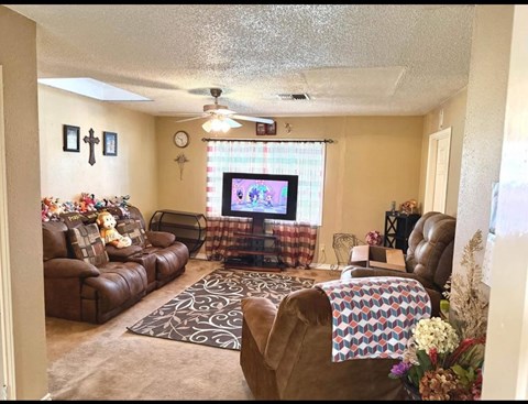 A living room with a brown leather couch and a television on the wall.