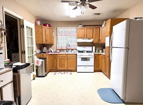 A kitchen with a white refrigerator, white stove, and wooden cabinets.