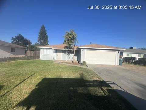 A house with a garage and a tree in front of it.