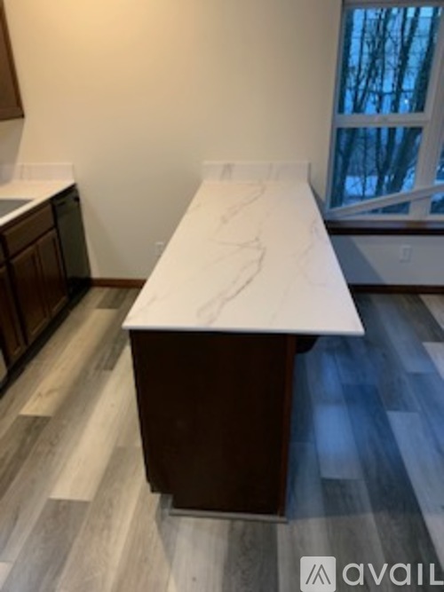 A long white countertop with a brown base sits in a kitchen.