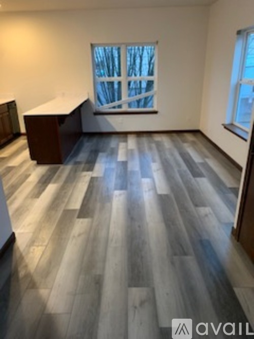 A room with wooden flooring and a window showing trees outside.