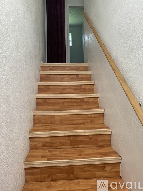A wooden staircase with a white wall on one side and a red curtain on the other.