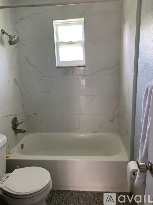 A bathroom with a marble wall and a white toilet.