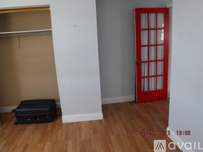 A room with a red door and a black box on the floor.