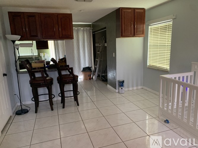 A baby's room with a crib and a kitchen area with bar stools.