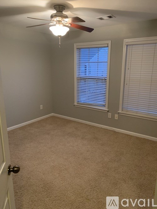 A room with a carpeted floor, a ceiling fan, and a window with blinds.