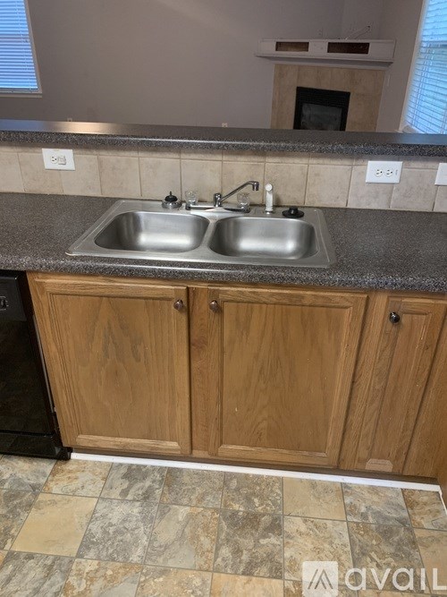 A kitchen with a double sink and wooden cabinets.