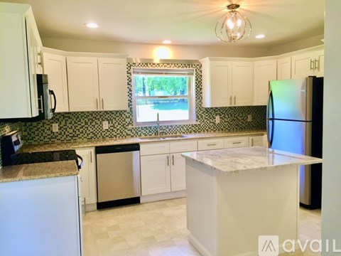 A kitchen with white cabinets and a black and white tiled backsplash.