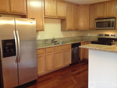 A kitchen with wooden cabinets and a stainless steel refrigerator.