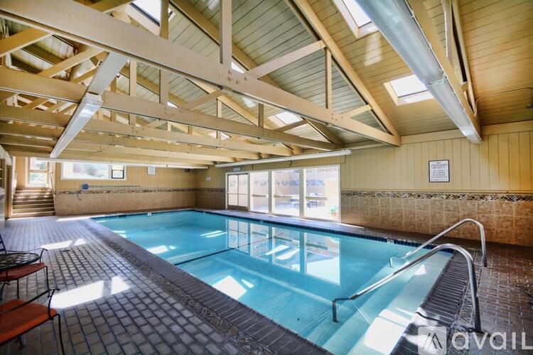 A large indoor swimming pool with a wooden ceiling and tiled floor.