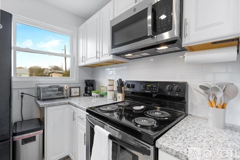 A kitchen with a black stove top oven and white cabinets.
