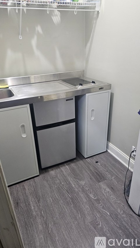 A kitchen area with a sink, two cabinets, and a hose.