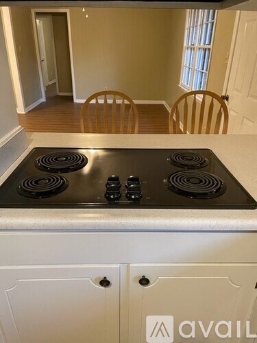 A stove top with four burners and knobs is in a kitchen.