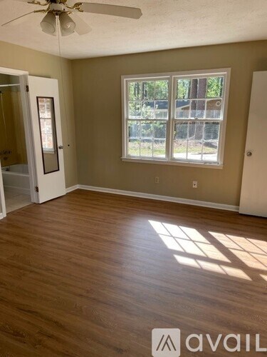 A room with wooden floors and a window with a view of trees.