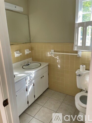 A bathroom with a toilet, sink, and mirror.