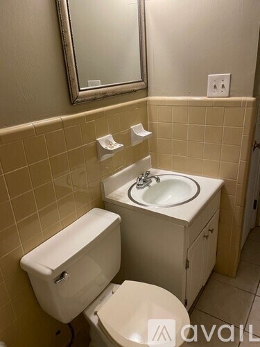 A bathroom with a toilet, sink, and mirror.